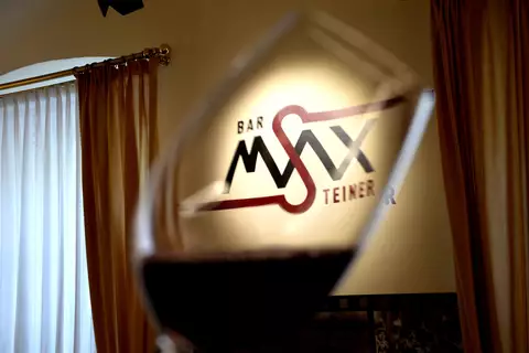 Detailaufnahme eines Weinglas vor dem Logo der Hotelbar