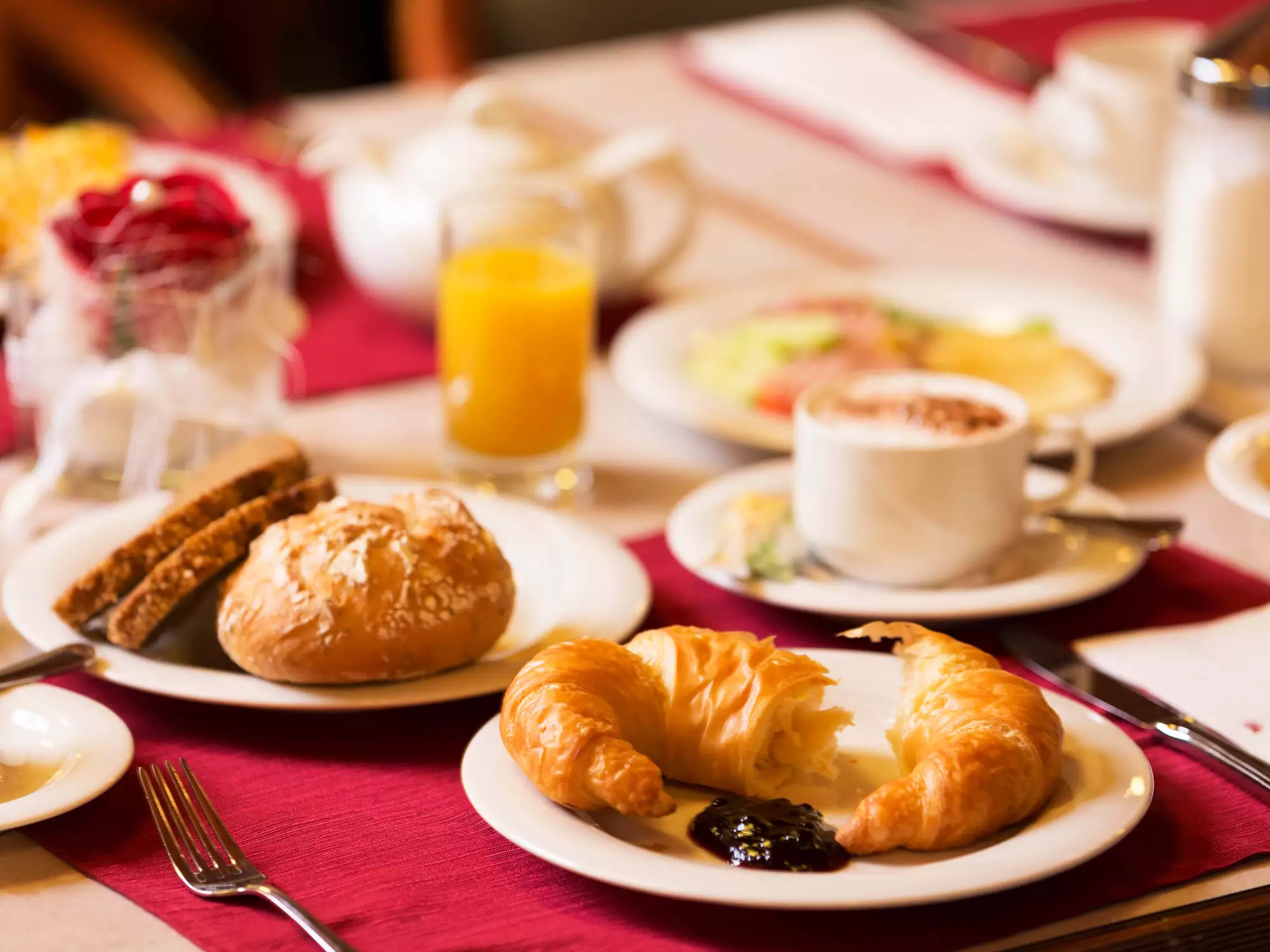 Ein liebevoll gedeckter Frühstückstisch mit einer Tasse Kaffee, frischen Croissants und einem Glas Orangensaft.