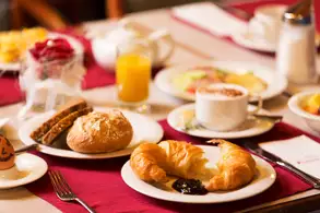 Ein liebevoll gedeckter Frühstückstisch mit einer Tasse Kaffee, frischen Croissants und einem Glas Orangensaft.